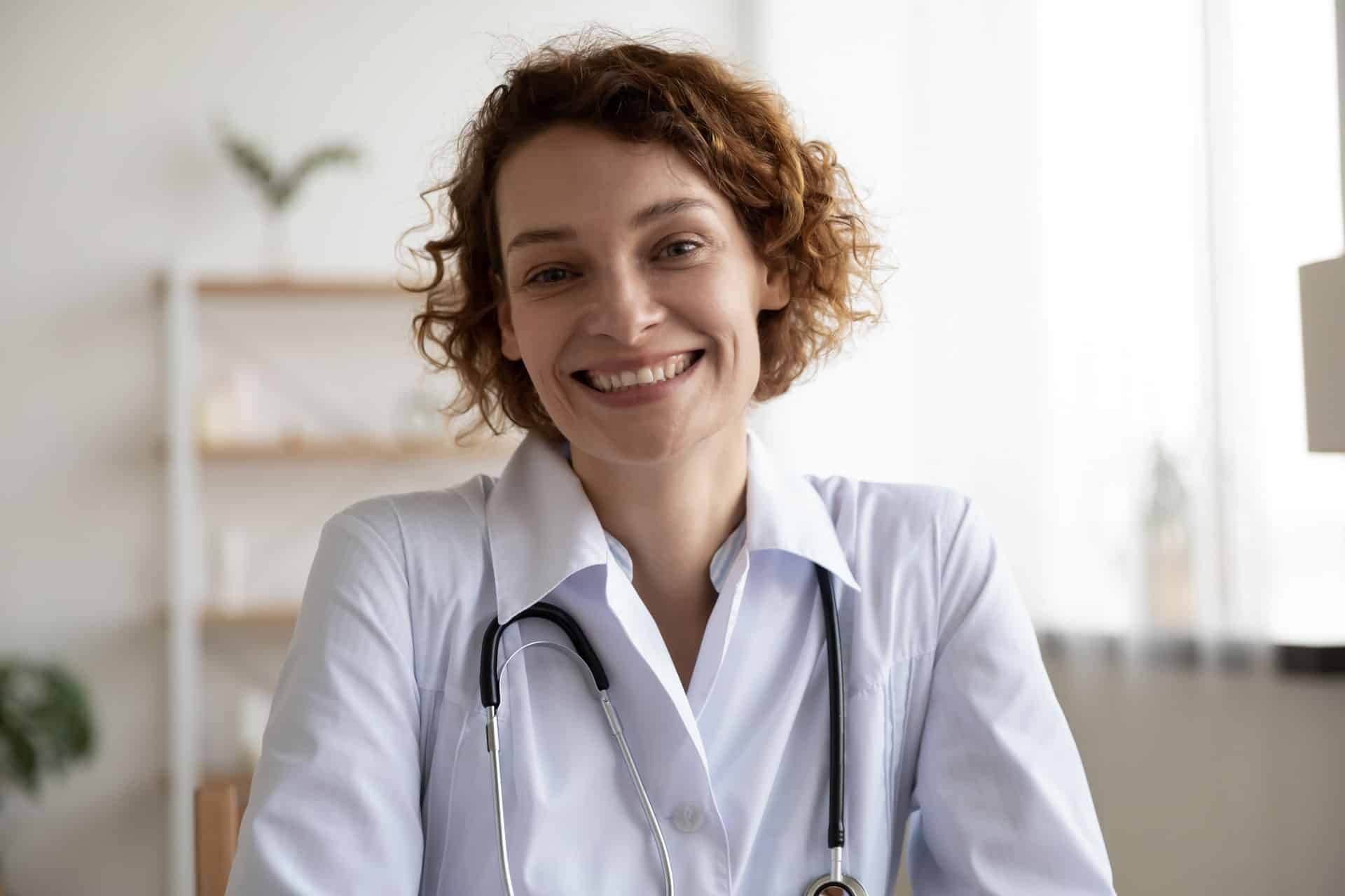 Happy woman doctor wears white medical coat looking at camera
