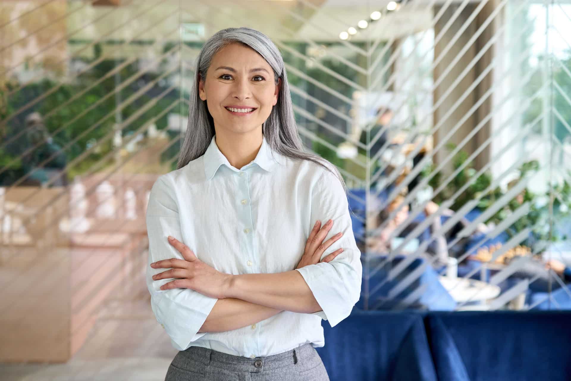 Happy confident senior Asian businesswoman standing in modern office. Portrait.